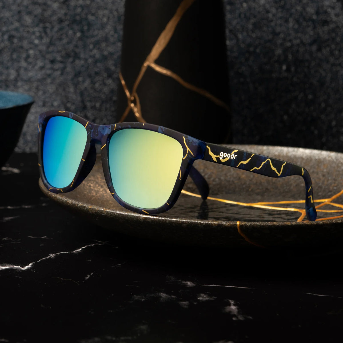 Multi-coloured square-shaped sunglasses with teal-coloured mirrored lenses. 