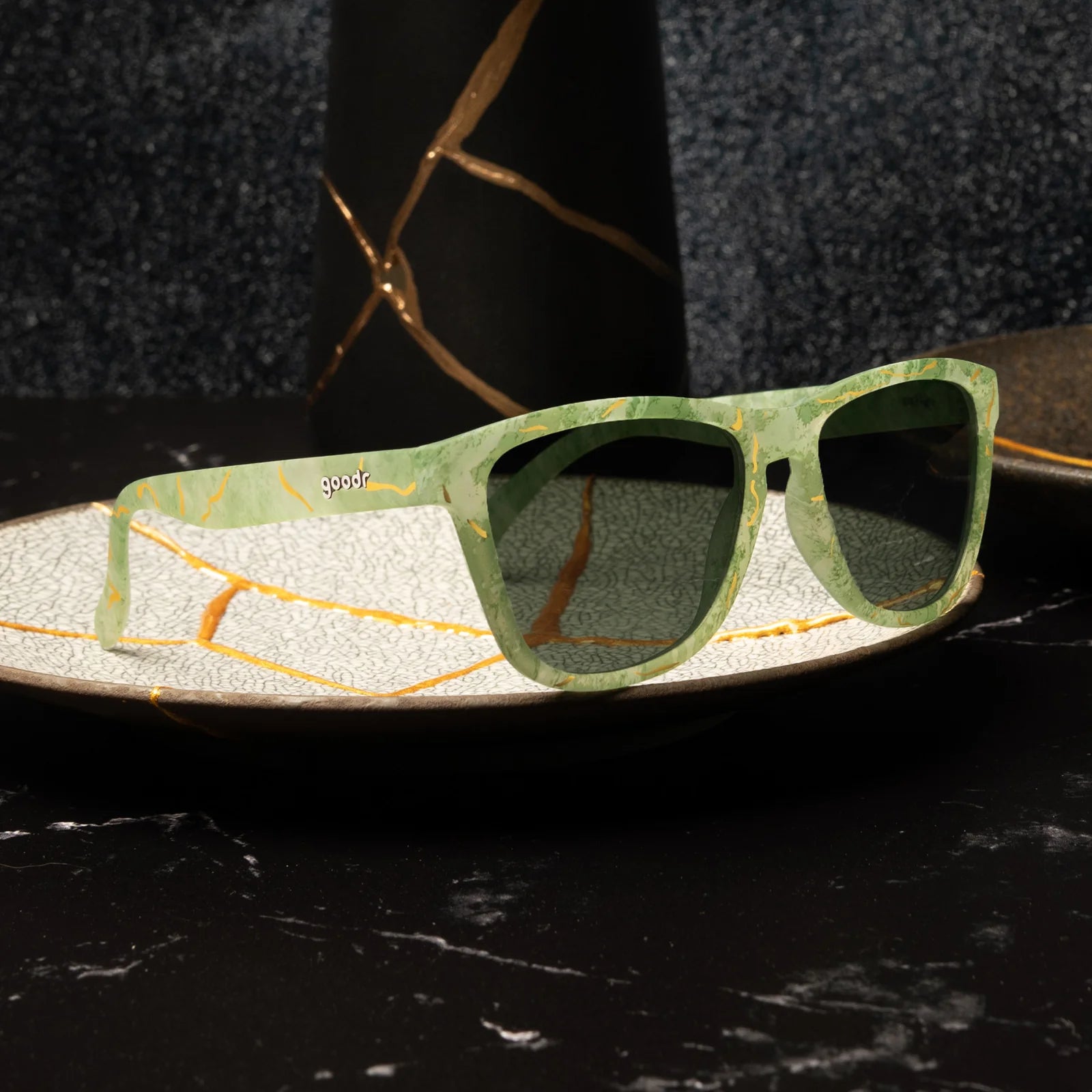 Marbled green square shaped sunglasses with a prominent golden line pattern, reminiscent of Kintsugi. 